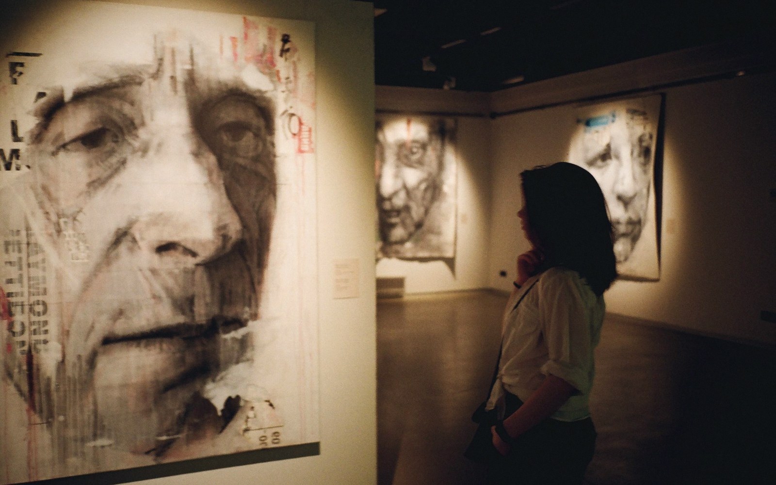 A single adult visitor standing before a very large painting, seen from behind, giving scale to the canvas
